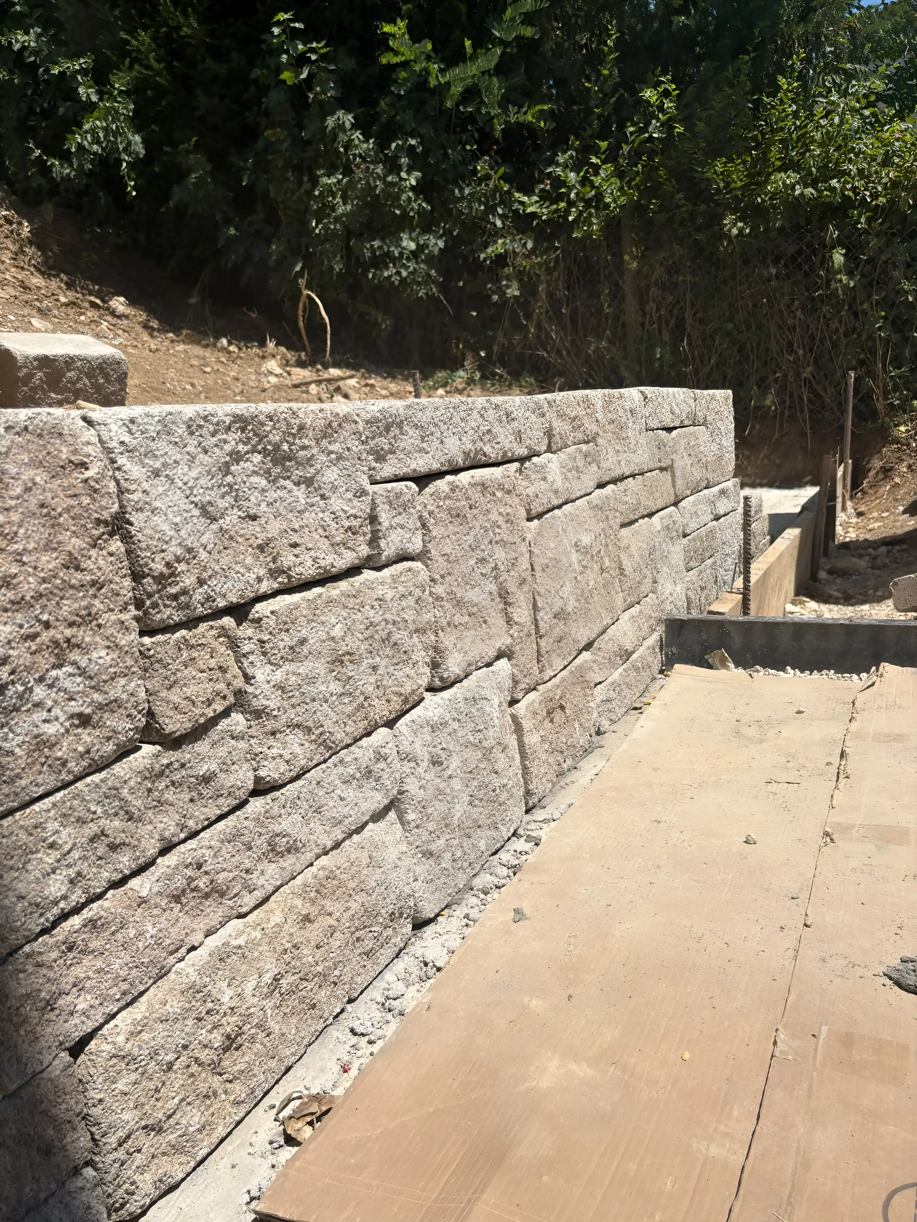 Mur de soutènement en gros blocs de pierre, marches en cours de pose